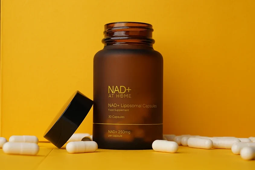 Open bottle of liposomal NAD+ capsules displayed with capsules on a yellow background.